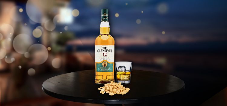 Glenlivet on desk with glass and peanuts