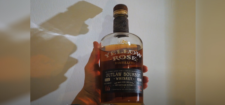 hand holding bottle of Yellow Rose Distilling Outlaw Bourbon Whiskey