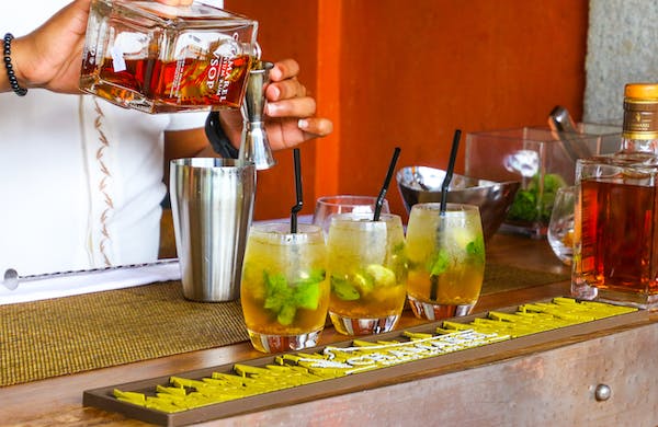 bourbon on the rocks garnished with lemon and mint leaves prepared by the bartender